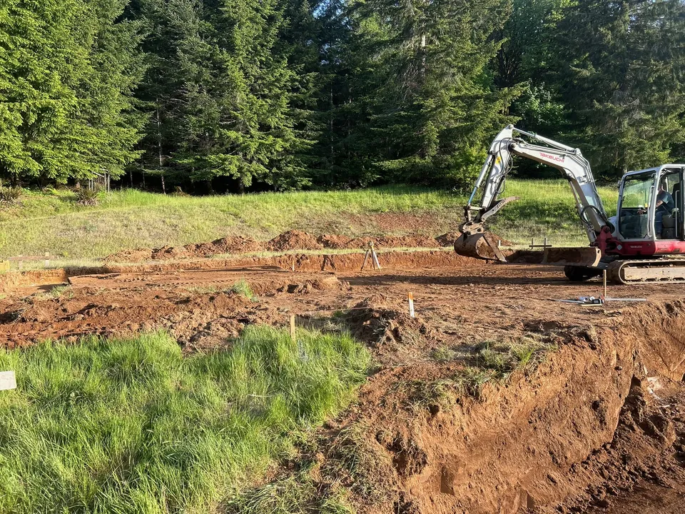 Excavated building site with stepped earthwork and a compact excavator